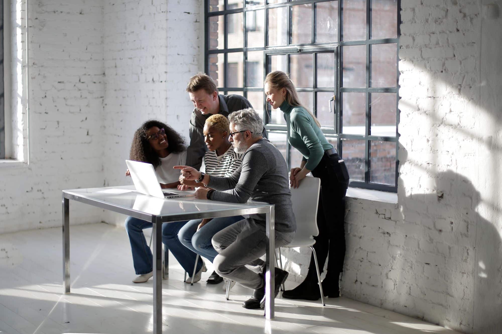 Colleagues gather around a laptop to review work together.