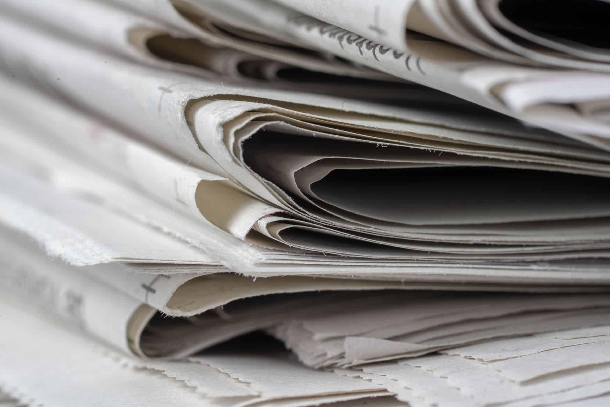 A close-up of folded newspapers stacked together.