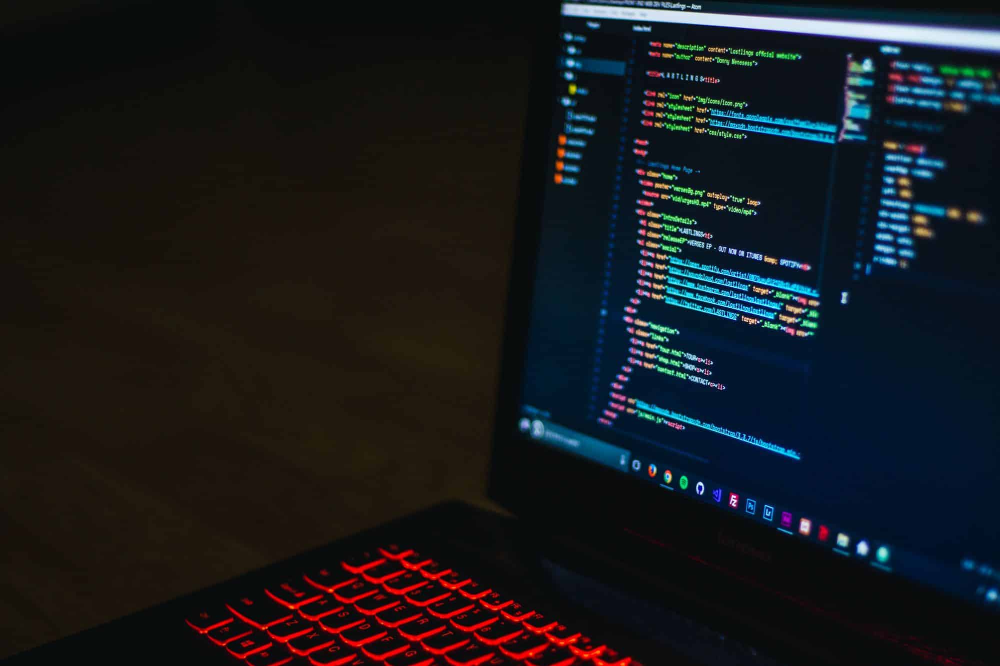 A laptop with a red backlit keyboard and code on its screen.
